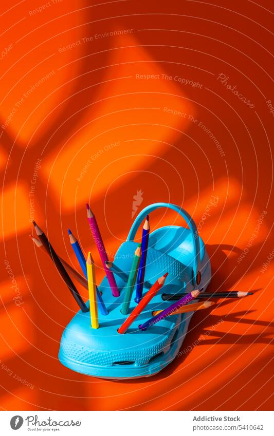Bunte Stifte in die Löcher der blauen Clogs Schuh farbenfroh Bleistift Golfloch kreativ Kunststoff Schuhe Farbe hell Gerät orange lebhaft pulsierend mehrfarbig