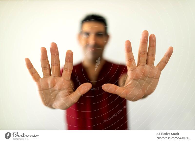 Unscharfer ethnischer erwachsener Mann zeigt offene Finger Lächeln Porträt freundlich selbstbewusst Masseur Therapeut gestikulieren zeigen Handfläche männlich