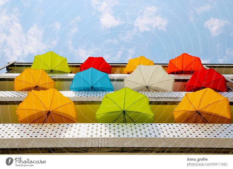 Viele bunte Sonnenschirme auf Balkonen mit Ansicht von unten mehrere sonnenschirme sonnenschutz hitzeschutz Sommer Schönes Wetter Außenaufnahme orange grün rot