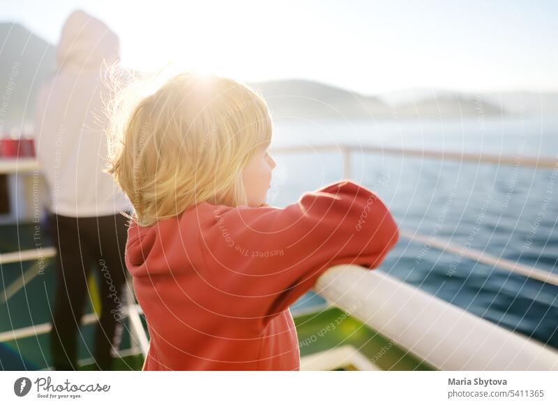 Blondes kleines Kind reist mit seiner Familie auf einer Fähre oder einem Schiff. Schuljunge bewundert die Landschaft der Adria. Kreuzfahrt in den Ferien.