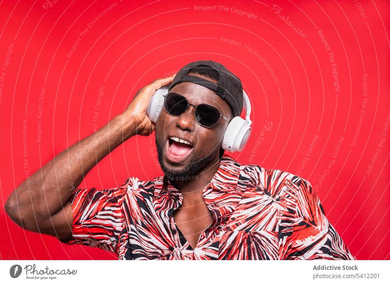 Glücklicher schwarzer Mann mit Sonnenbrille und Kopfhörern Stil erstaunt Überraschung Porträt Mund geöffnet Erstaunen Verschlussdeckel modern männlich Schock