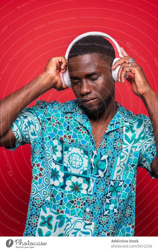 Fröhlicher afroamerikanischer Mann spielt Musik mit Kopfhörern zuhören Gesang Audio genießen Drahtlos Melodie trendy benutzend Klang Afroamerikaner Gerät Stil