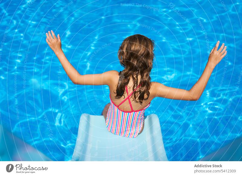 Rückenansicht eines Mädchens mit erhobenen Händen an der Spitze einer Rutsche im Schwimmbad schwimmen Pool Urlaub Sommer Wasser Resort Badebekleidung MEER