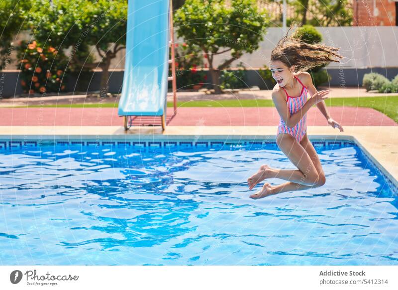 Mädchen springt ins Wasser mit Bäumen am Beckenrand springen Pool Sommer schwimmen Urlaub heiter Resort Lächeln Sinkflug genießen Bewegung Glück Aktivität Frau