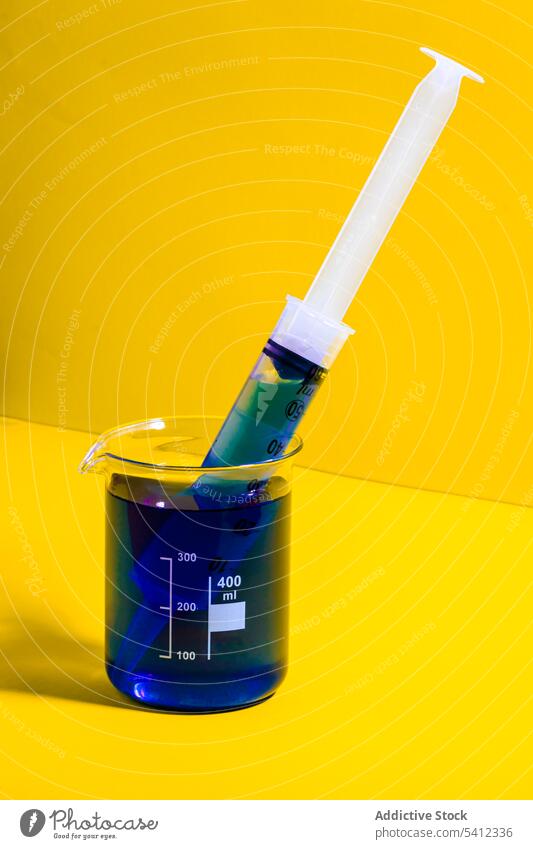 Spritze im Glas mit blauer Flüssigkeit liquide Nadel Kunststoff durchsichtig Medizin Chemikalie Humpen steril Dosis Einspritzung medizinisch Impfstoff