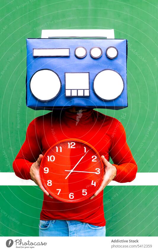 Anonyme Person mit Boombox und Uhr im Studio Mann Deckblatt Zeit Musik zuhören Konzept Tierhaut Frist Stunde Minute punktuell lässig hell Individualität rot