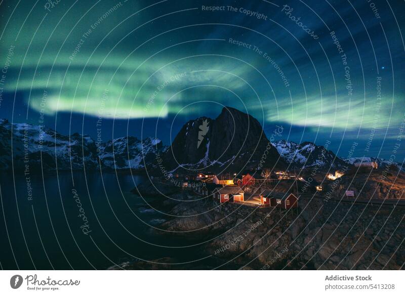 Erstaunliche Aussicht auf Nordlichter über schneebedeckten Bergen beleuchtete Gebäude in dunkler Nacht spektakulär nördlich Licht polar Aurora Berge u. Gebirge