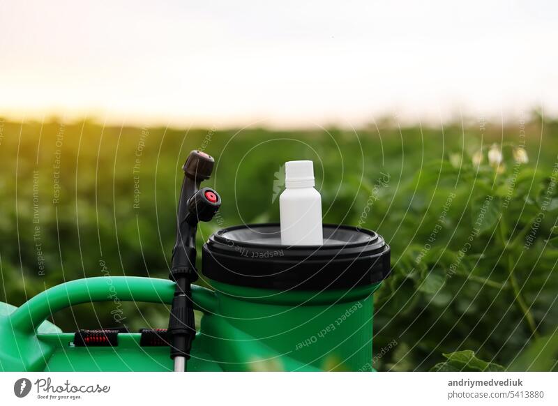 Weiße kleine Flasche von Pestizid, Herbizid für den Schutz von Pflanzen vor Krankheiten und Schädlingen mit Mock up steht auf Container Sprayer auf natürliche grüne Garten Hintergrund. Landwirtschaftliche saisonale Arbeit