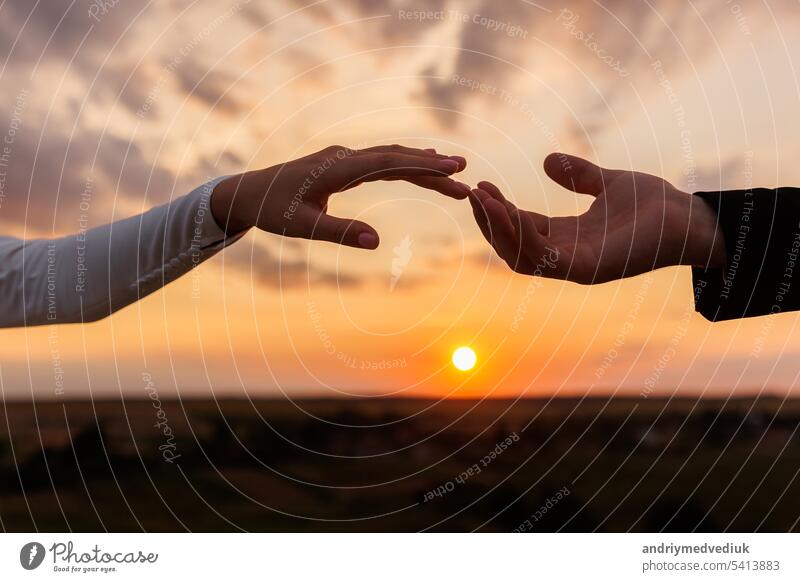 Hände von Braut und Bräutigam erreichen einander, berühren Finger auf Sonnenuntergang Himmel Landschaft Hintergrund. Helfende Hände für speichern und unterstützen Menschen Konzept. Hochzeitstag. Valentinstag.