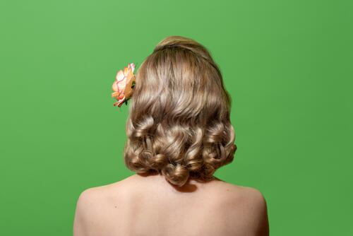 Porträt einer blonden Frau mit lockigem Haar im Retrostil, isoliert auf grünem Hintergrund 40s 50s Zubehör Rücken Schönheit hell Farbe Konzept Textfreiraum