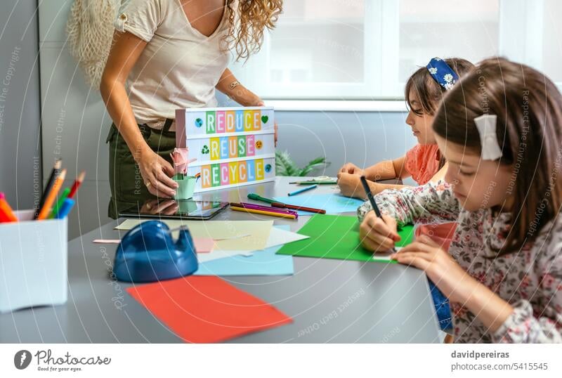 Lehrer hält Leuchtkasten mit Text "Reduzieren, wiederverwenden, recyceln", während Schüler im Klassenzimmer zeichnen unkenntlich Frau zeigend Beteiligung