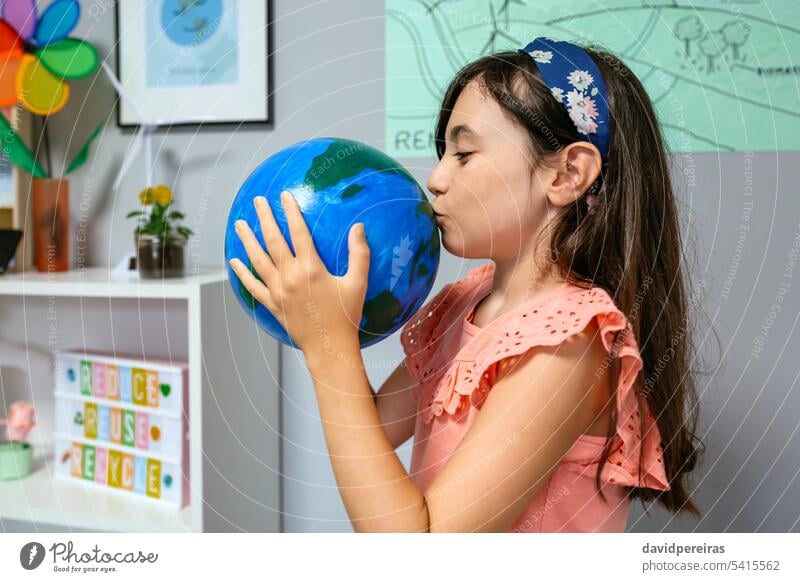 Studentin küsst eine handgefertigte Weltkugel im Ökologie-Klassenzimmer Schüler Küssen Globus Erde Planet Hand Frau Liebe wenig Mädchen Schule lustig Glück