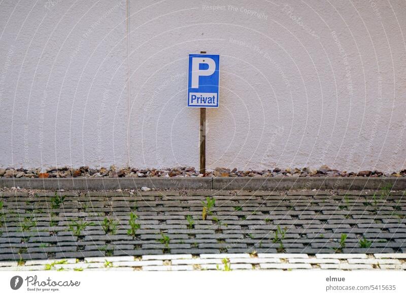 Parkplatzschild mit dem Zusatz Privat im Schatten vor einer Hauswand und hinter einer gepflasterten Parkfläche Parkschild privat Privatparkplatz Schild parken