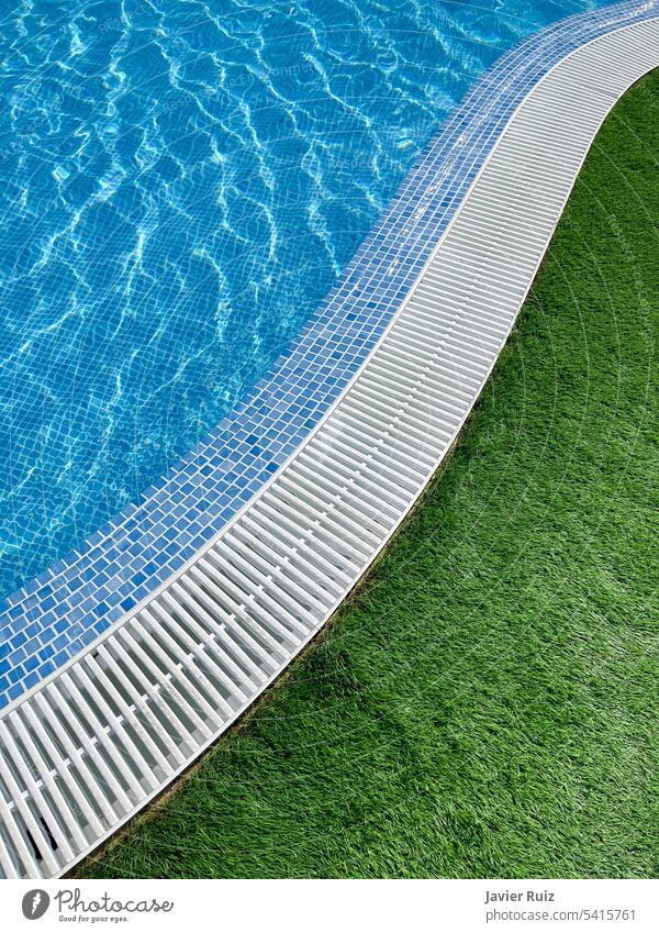 Rand eines s-förmigen Schwimmbeckens mit kristallklarem Wasser, weißem Spalier und grünem Gras Schwimmsport Pool Sommer blau übersichtlich s-Form vertikal