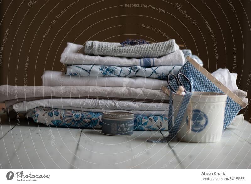 Stapel gefalteter Wäsche mit Topf mit Kurzwarenausrüstung Wäscherei Laken Streu Wäsche waschen Kurzwarenhandlung blau und weiß Leinen Wäscheschrank