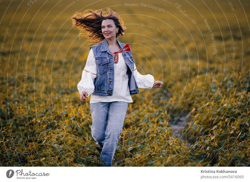 Glückliche Frau läuft im grünen Feld. Junge Frau in weißer Stickerei Ethno-Shirt. Ukrainer jung schön Schönheit Mädchen Person stylisch Porträt Kaukasier