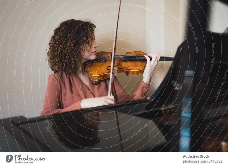 Schwangere Frau spielt auf Geige in der Nähe von Klavier im Zimmer schwanger Musiker Spielen Raum attraktiv jung krause Haare schön geschlossene Augen Bauch