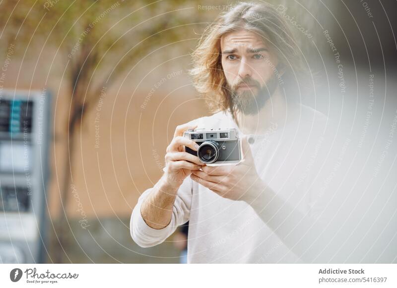 Gut aussehender Mann, der die Kamera in der Hand hält gutaussehend fotografierend schwarz besinnlich Fotograf Schnurrbart Fotokamera Bartstoppel Erwachsener Hut