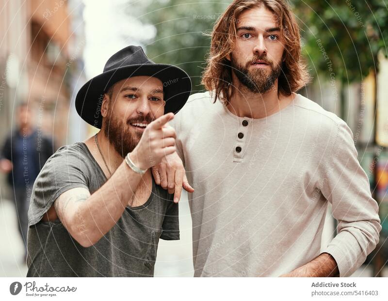 Hübsche Männer stehen auf der Straße und beobachten Zeigen Freundschaft Schnurrbart Lächeln Erwachsener gutaussehend Lifestyle Zusammensein zeigend Bartstoppel
