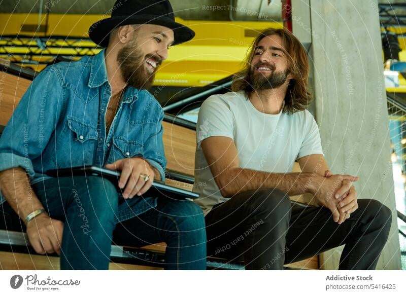 Männer sitzen auf der Treppe und unterhalten sich angeregt gutaussehend Freundschaft Lächeln Diskussion über sprechend genießend Erwachsener plaudernd Lifestyle