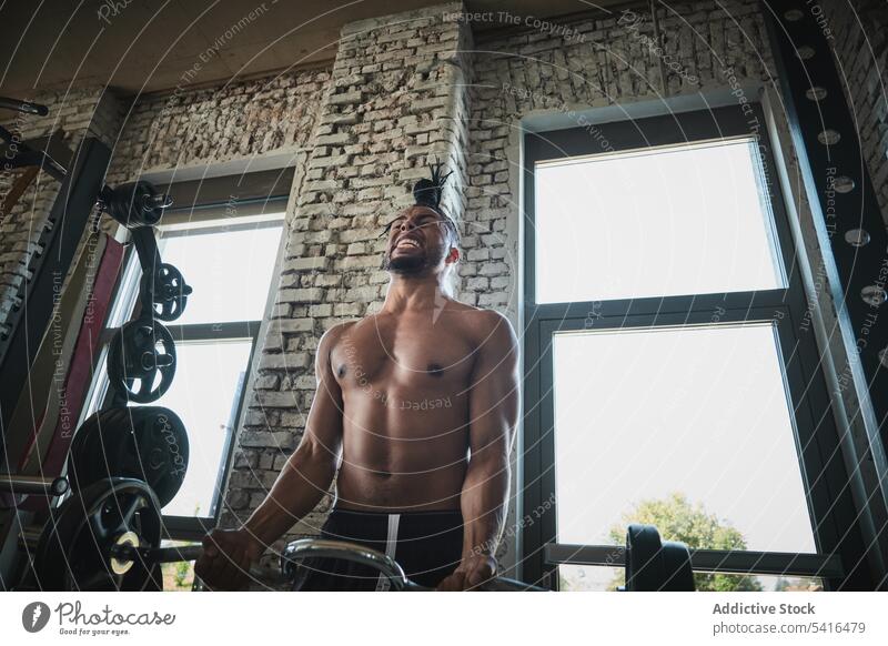 Schwarzer Mann trainiert mit Langhantel im Fitnessstudio Afrikanisch Amerikaner schwarz Heben Curl-Hantel ohne Hemd Training Übung Gewicht männlich passen stark