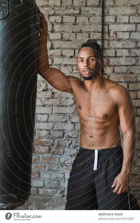 Selbstbewusster schwarzer Boxer im Fitnessstudio Mann Boxsport Tasche Afroamerikaner ohne Hemd Lehnen muskulös Sport Training männlich Stärke Kraft Tatkraft