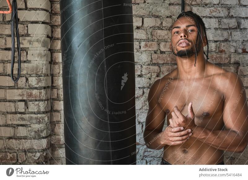 Selbstbewusster schwarzer Boxer im Fitnessstudio Mann Boxsport Tasche Afroamerikaner ohne Hemd Lehnen muskulös Sport Training männlich Stärke Kraft Tatkraft