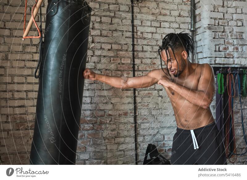 Schwarzer Mann boxt im Fitnessstudio Boxsport Tasche Stanzen Training ohne Hemd Afroamerikaner Sport muskulös männlich jung Athlet Stärke Kraft Kämpfer passen