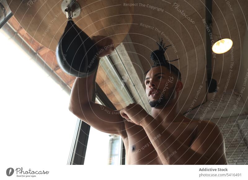 Schwarzer Mann boxt im Fitnessstudio Boxsport Tasche Stanzen Training ohne Hemd Afroamerikaner Sport muskulös männlich jung Athlet Stärke Kraft Kämpfer passen
