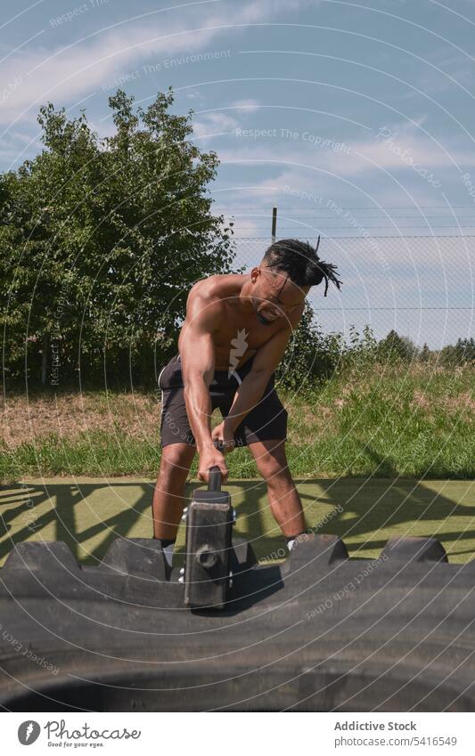 Muskulöser schwarzer Mann hämmert Reifen in einem Fitnessstudio im Freien Hammer Übung schlagend ohne Hemd muskulös anstrengen Training Athlet männlich Sport