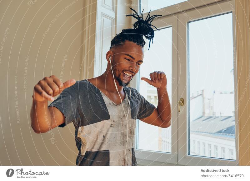 Fröhlicher ethnischer Mann beim Musikhören Frisur cornrows geflochten Kopfhörer Tanzen Daumen hoch jung männlich Afroamerikaner Person gutaussehend positiv