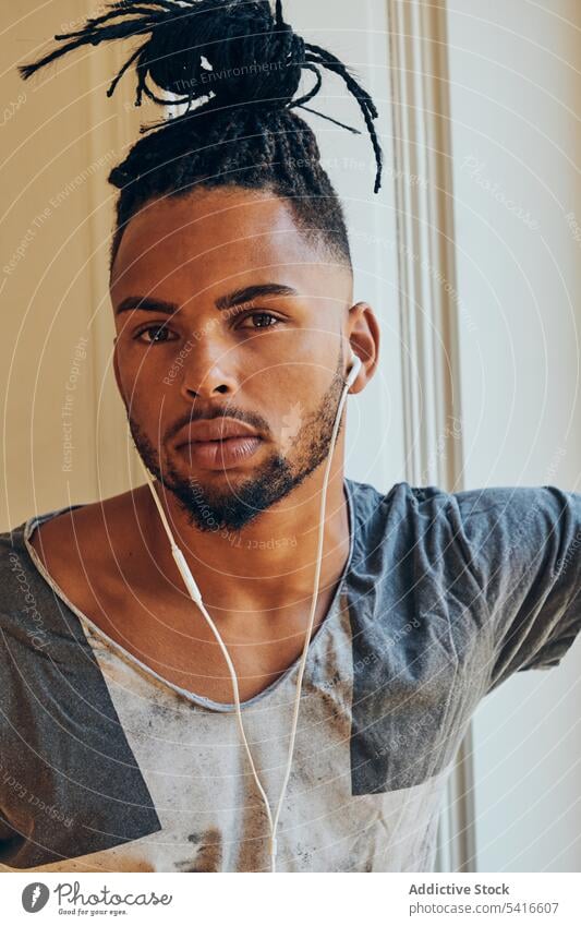 Afroamerikanischer Mann schaut aus dem Fenster ethnisch geflochten Frisur Zöpfe kreativ Kopfhörer Musik jung männlich Afroamerikaner Person gutaussehend
