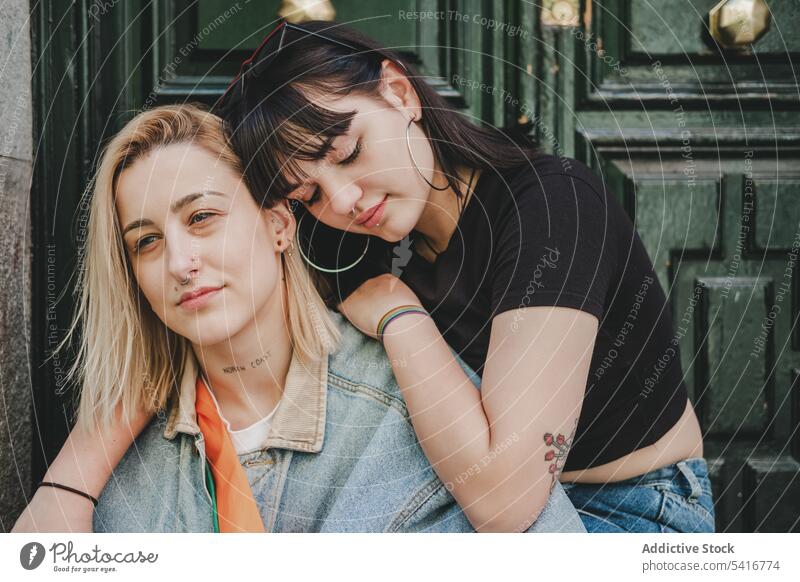 Lesbisches Paar sitzt in der Nähe der Tür lesbisch umarmend Frauen Liebe Sitzen Straße Großstadt Gebäude jung lässig geschlossene Augen Angebot Homosexualität