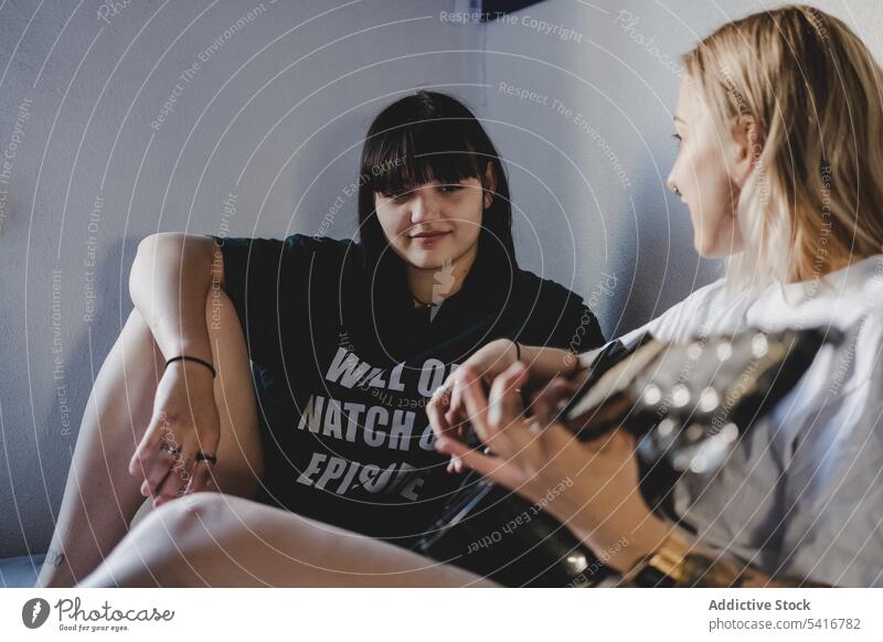 Lesbisches Paar spielt Gitarre auf dem Bett lesbisch Spielen heimwärts Sitzen heiter die sich gegenseitig ansehen jung Partnerschaft Frauen lgbt romantisch