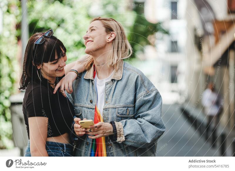 Lesbisches Paar telefoniert auf der Straße lesbisch Smartphone lgbt Glück Großstadt jung Zusammensein Frauen lässig Homosexualität Stolz Gleichstellung