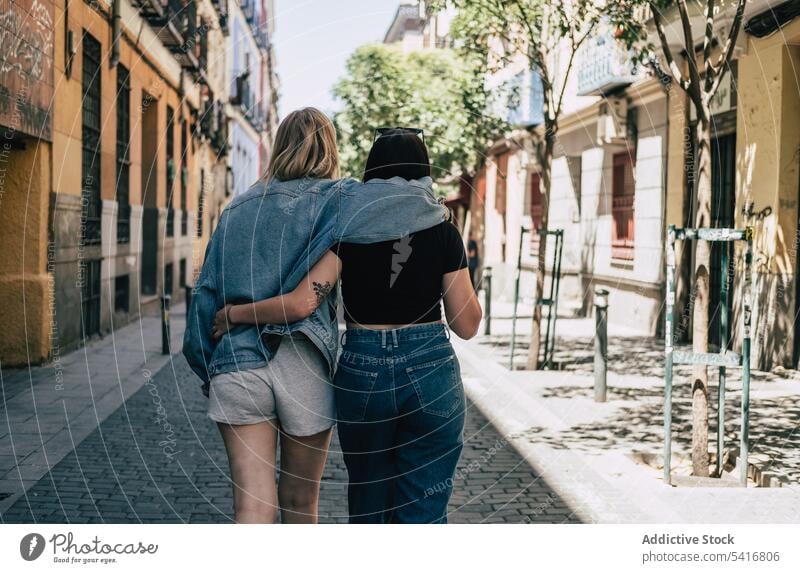 Lesbisches Paar, das sich umarmt und auf der Straße geht lesbisch lgbt laufen umarmend Glück winkend Großstadt jung Zusammensein Frauen lässig Homosexualität