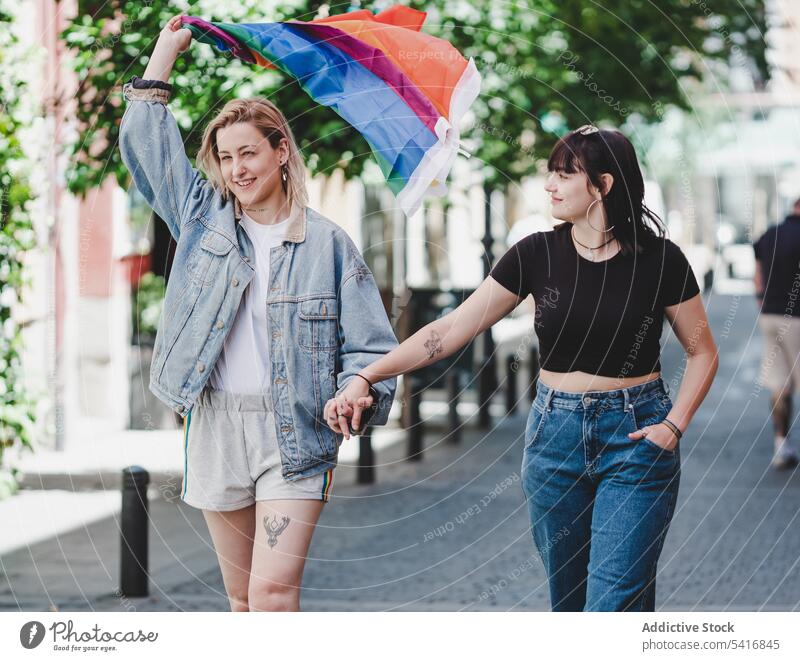 Lesbisches Paar mit LGBT-Flagge auf der Straße lesbisch Fahne lgbt laufen Glück winkend Großstadt jung Zusammensein Frauen lässig Homosexualität Stolz