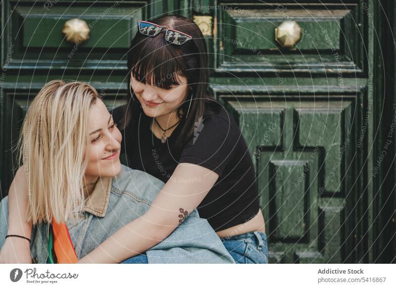 Lesbisches Paar sitzt in der Nähe der Tür Gefühle Glück Lächeln umarmend Stadt schön alternativ Zusammensein Homosexualität Frauen Lifestyle Partnerschaft