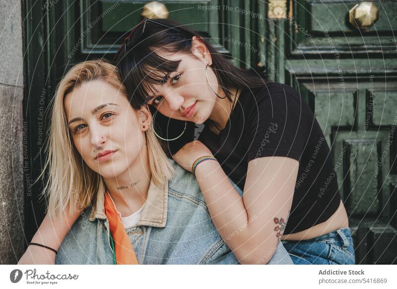 Lesbisches Paar sitzt in der Nähe der Tür lesbisch umarmend Frauen Liebe Sitzen Straße Großstadt Gebäude jung lässig Angebot Homosexualität lgbt alternativ