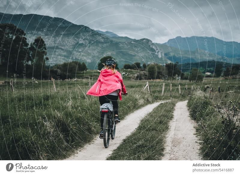 Radfahrerin fährt auf einer Bergstraße Frau Fahrrad Reiten Straße Schutzhelm felsig Rückansicht Berge u. Gebirge Landschaft Erwachsener Person aktiv sportlich