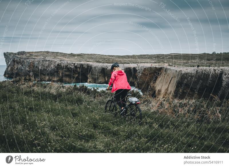 Frau auf Fahrrad genießt Landschaft Schutzhelm Mitfahrgelegenheit Klippe MEER Erwachsener Person aktiv blond Fahrradfahren genießend zuschauend Blick