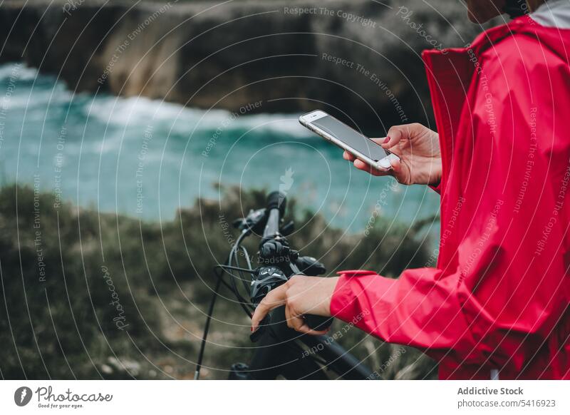 Anonyme Fahrradfahrerin mit Smartphone Frau Hand unkenntlich Mitfahrgelegenheit Landschaft Erwachsener Person blond benutzend Texten Browsen Touchscreen