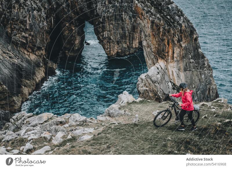 Radfahrerin auf Felsen Frau Fahrrad Klippe anonym Schutzhelm MEER Landschaft extrem jung Person heiter sportlich Lächeln laufen Lifestyle Mitfahrgelegenheit