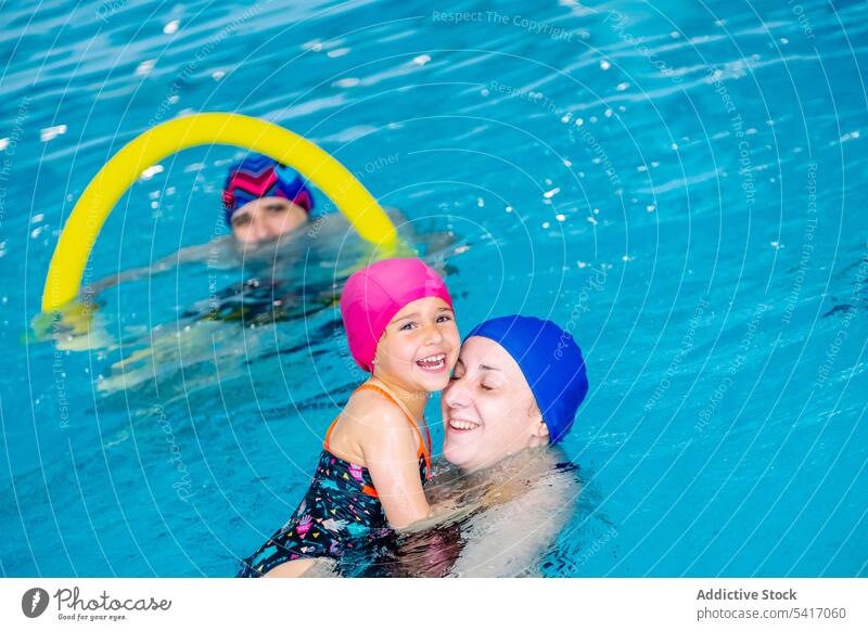 Fröhliches Mädchen schwimmt mit Mutter im Pool Schwimmsport Wasser Park aufgeregt Spaß Wochenende Zusammensein Vergnügen Frau Kind Schutzbrille Hut heiter Glück