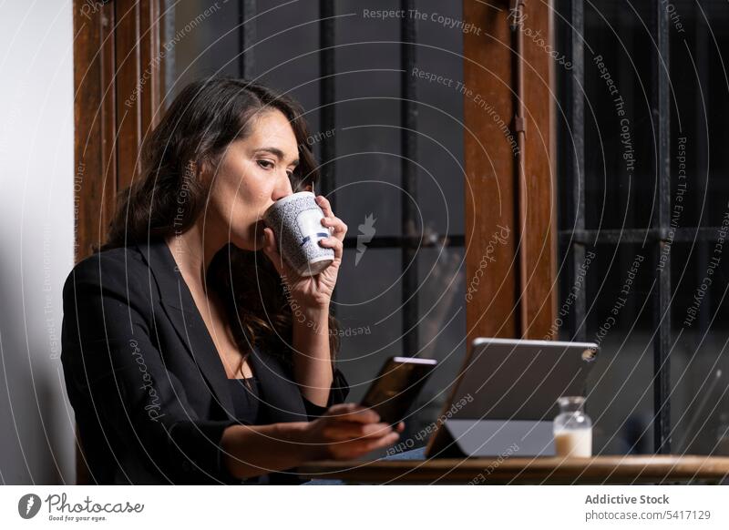 Junge Frau benutzt ein Mobiltelefon in einem Cafe Tablette Café Tasse Browsen Technik & Technologie Tee Kaffee jung Person attraktiv brünett schön hübsch Handy