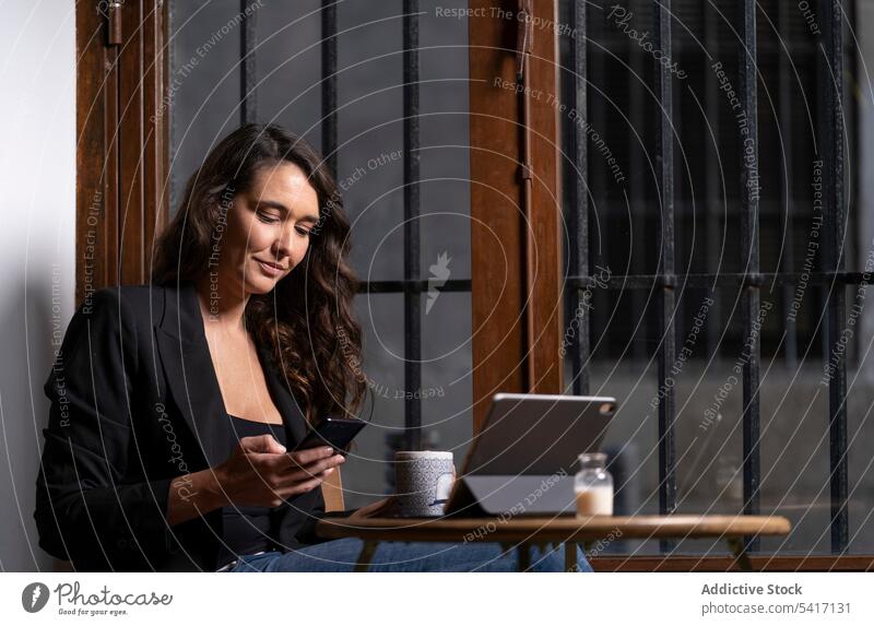 Junge Frau benutzt ein Mobiltelefon in einem Cafe Tablette Café Tasse Browsen Technik & Technologie Tee Kaffee jung Person attraktiv brünett schön hübsch Handy