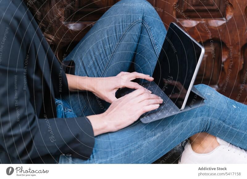 Junge Frau auf der Schwelle sitzend Tür Tablette Browsen Technik & Technologie jung Person brünett lässig modern stylisch verbunden Sitzen benutzend Texten