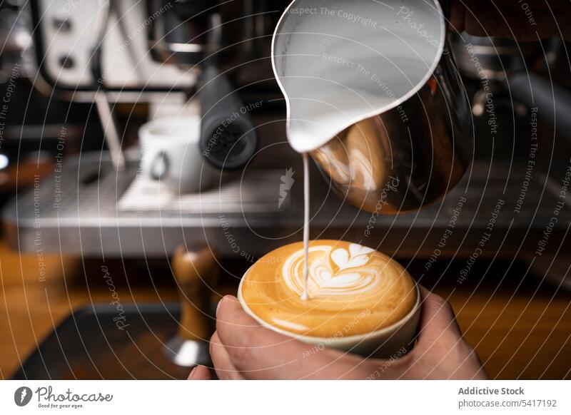 Barista macht Kaffee mit Latte Art Kunst Cappuccino Tasse Hand schäumen Getränk Muster Café Beruf Erwachsener Person professionell Gießen dekorierend heiß