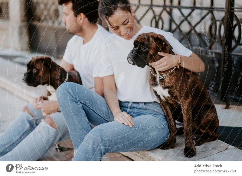 Liebenswerte Boxerhunde sitzen mit jungen Menschen Hund Freunde bezaubernd Fröhlichkeit Tier Haustier umarmend Freizeit amüsant Glück lustig niedlich