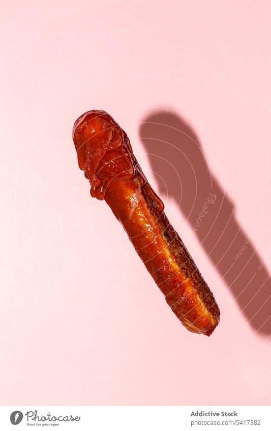 leckere gegrillte Wurst mit Ketchup vor einem rosa Hintergrund Beschneidungspfad Mahlzeit Gastronomie ungesund Nahaufnahme gebraten Fleisch vorbereitet